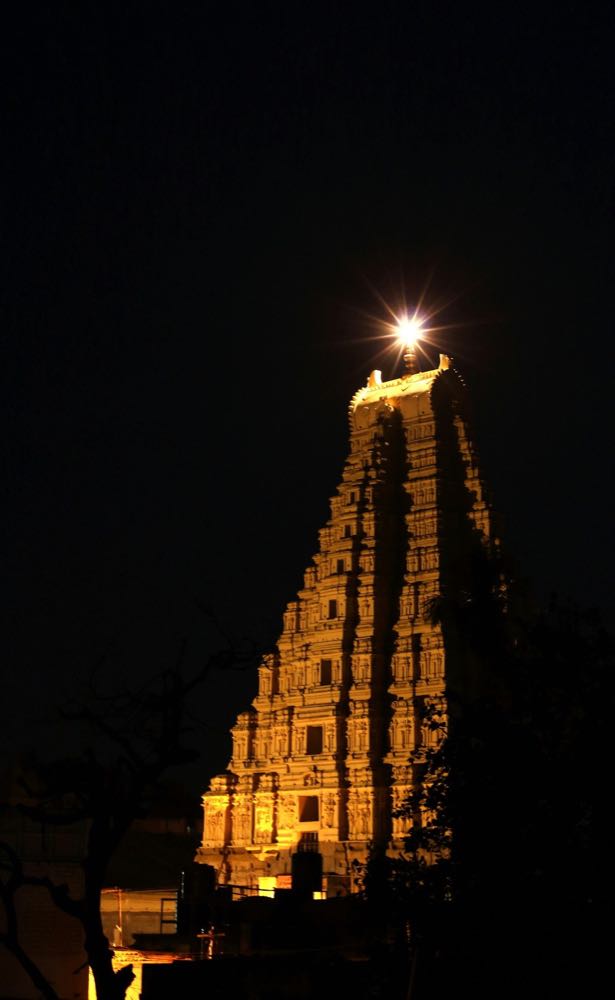 The Moon rising over the tower of a South Indian temple at night.